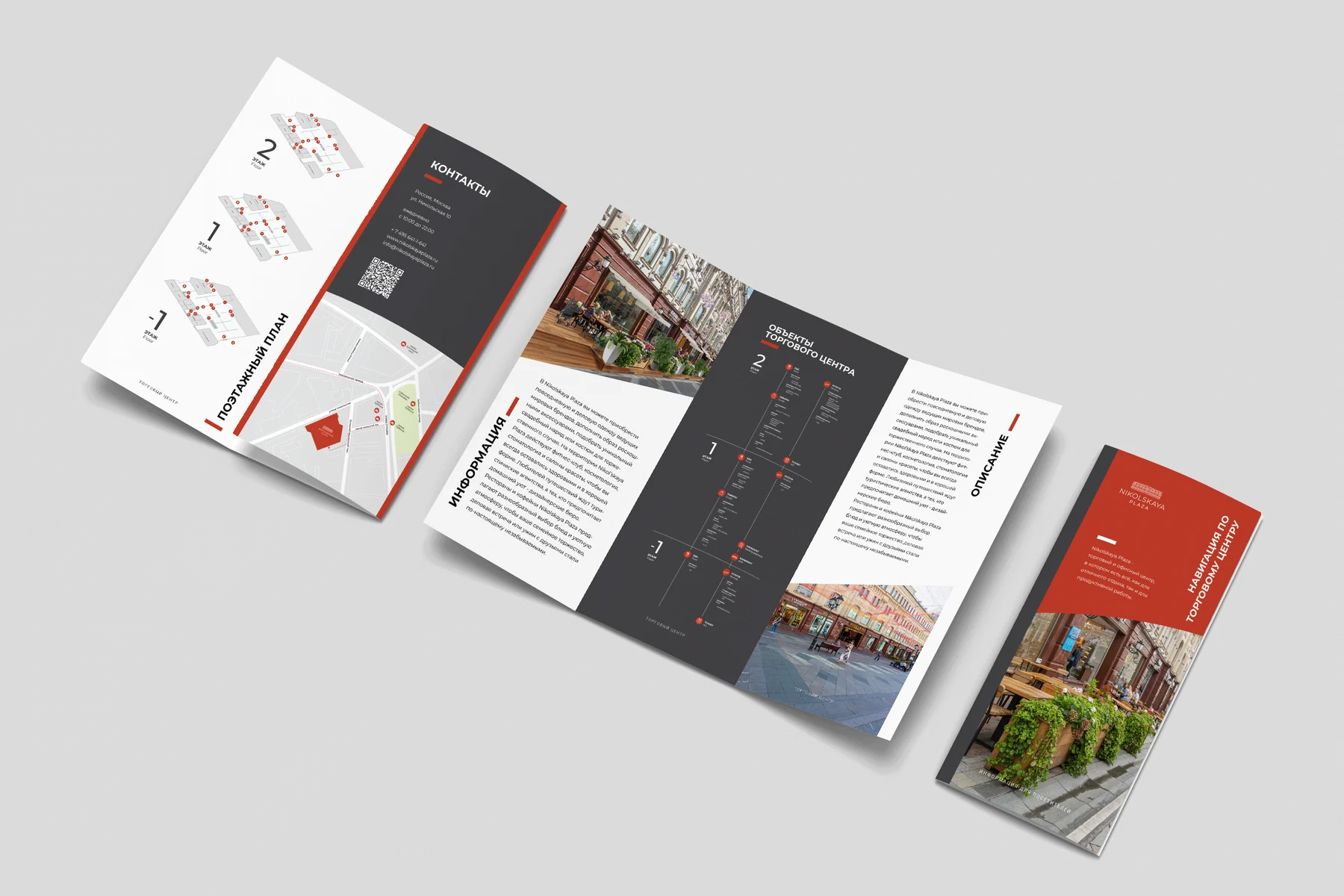 An accordion-folded leaflet standing open, showing floor plans, photographs of the building and dense text in red, white and dark grey.