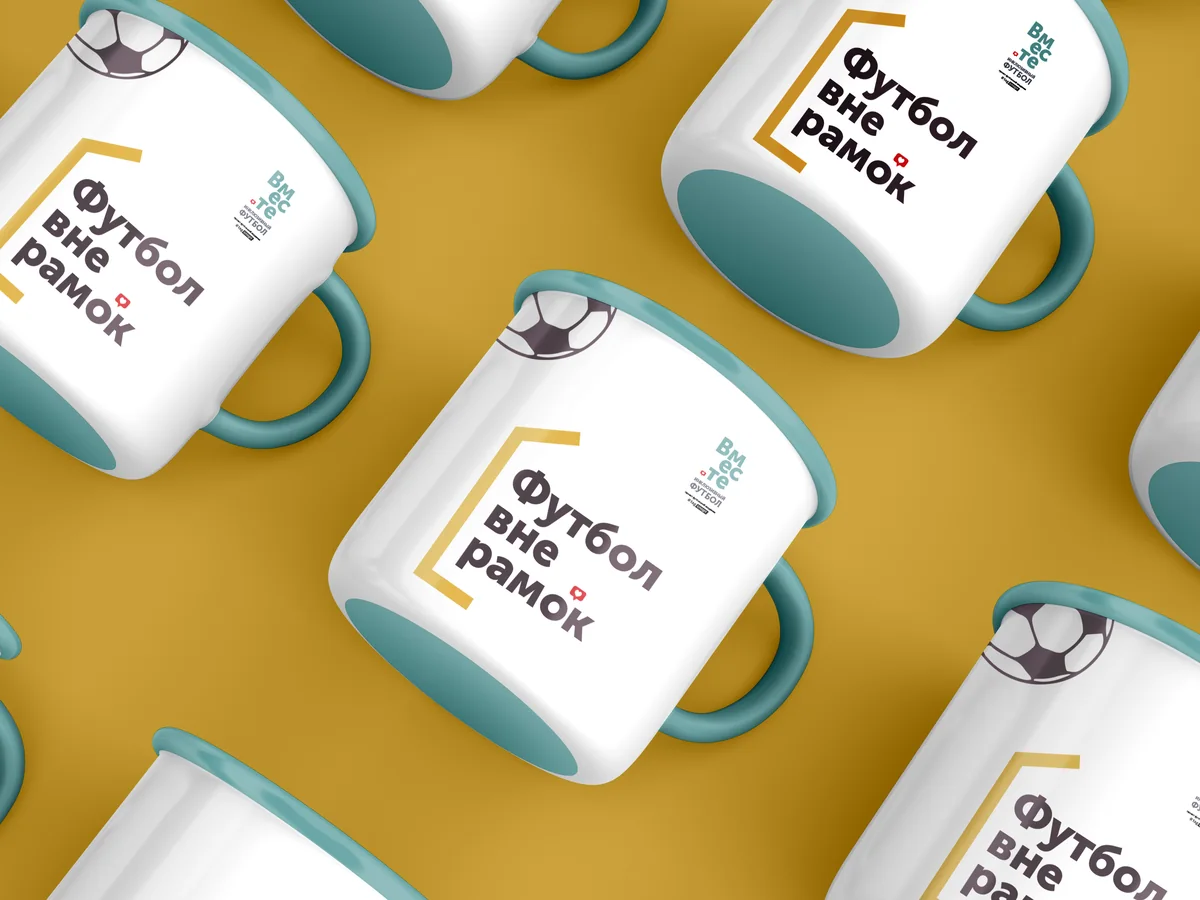 White enamel mugs with teal rims and handles, printed with Футбол вне рамок in a gold bracket and a football, arranged on a gold background.