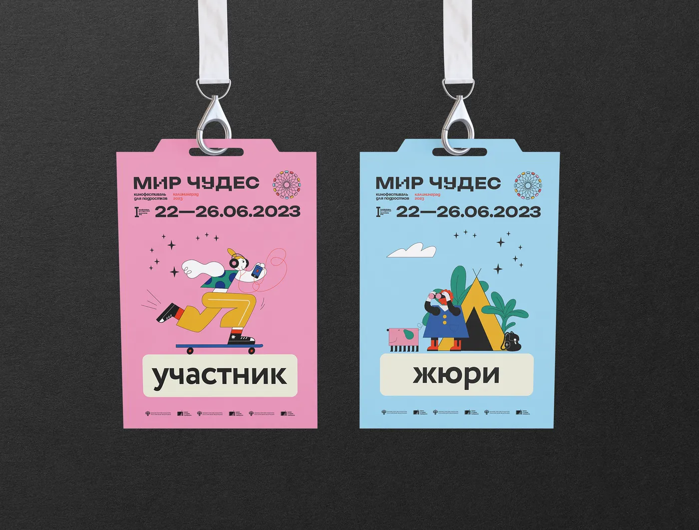 Two lanyard badges, pink for participants and sky blue for jury, each with an illustrated character and the festival dates.