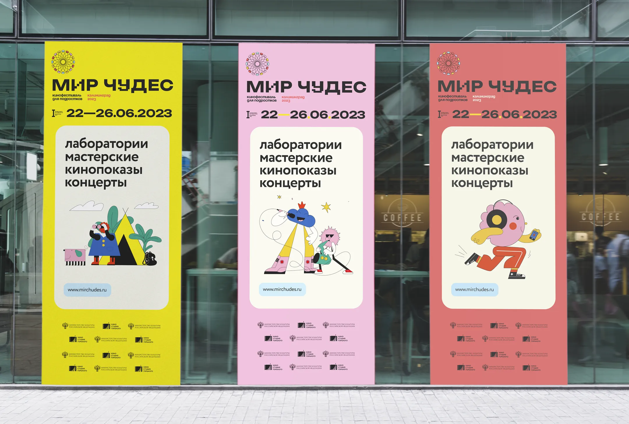 Three vertical festival banners hanging side by side on a glass facade — one lemon, two pink — each with a different illustrated character and the same programme lines.